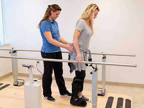 A women works to walk again after leg injury while wearing a boot.