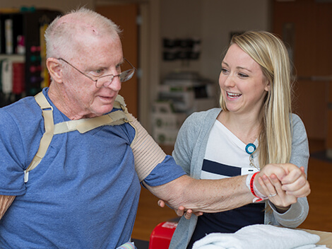 A female therapist works with her male patient to regain range of arm motion following a stroke.
