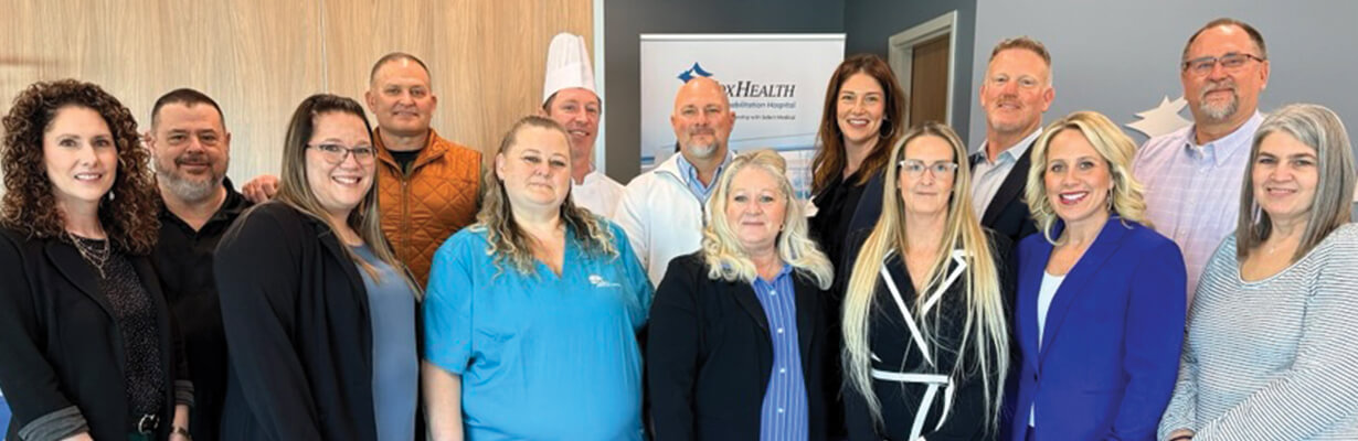 The CoxHealth Rehabilitation Hospital team gathers in the hospital lobby and smiles at the camera.