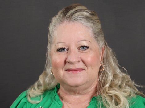Lisa Hallam smiles at the camera wearing a green blouse.