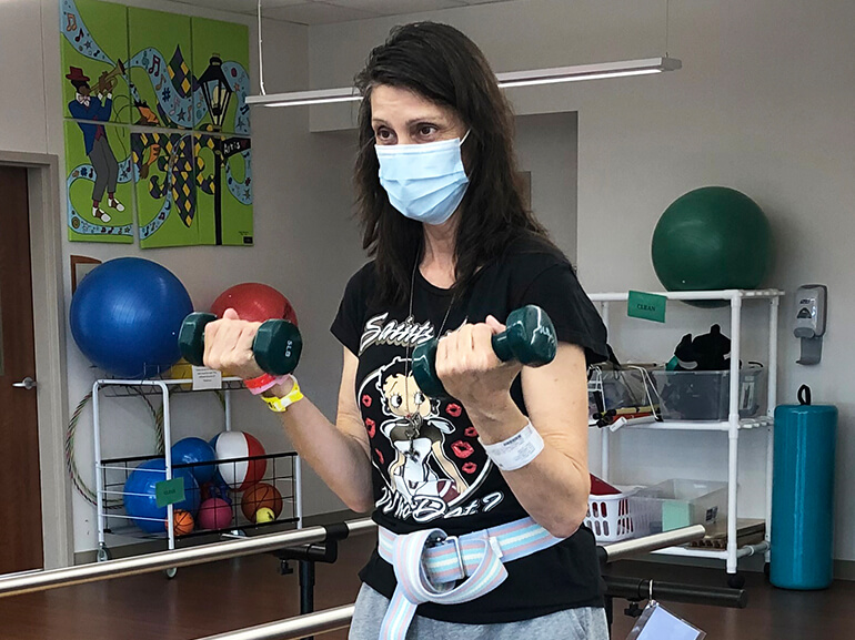 Woman with long, dark hair doing bicep curls with small handheld weights.