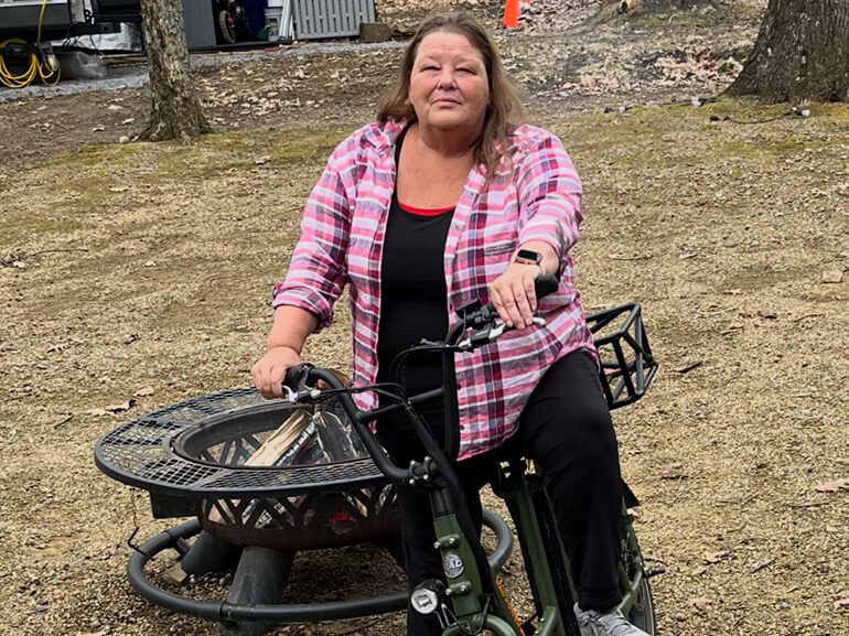 Peggy Downey stands with her bike following her recovery.