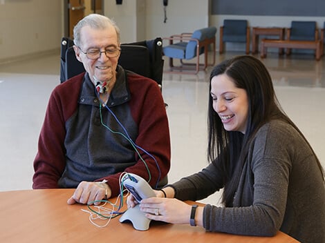 A female therapist works with a stroke patient to utilize advanced technology to rehabilitate swallowing muscles after stroke.