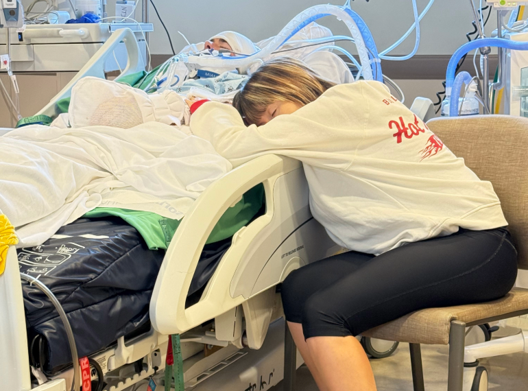 Kayla sleeping across Brian's hospital bed.