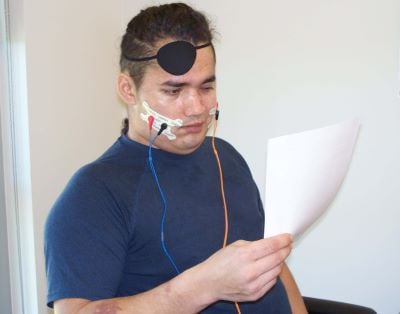 A stroke patient works with a speech language pathologist to use neuro-muscular electrical stimulation to the face during speech therapy.