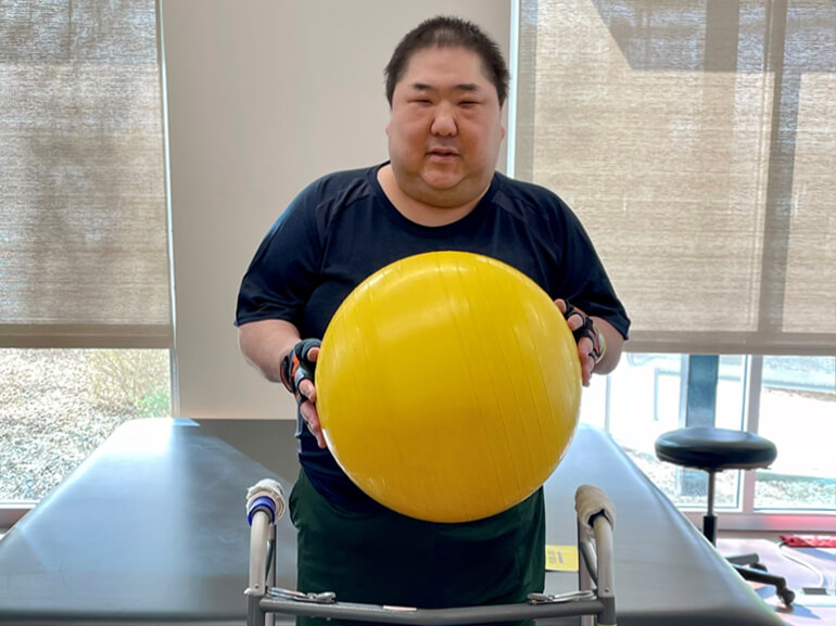 Joseph Lo holding  a therapy ball.